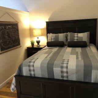 A cozy bedroom with a striped bedspread, bedside lamp, and wall art.