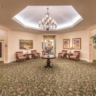 A spacious and elegantly designed lobby featuring a chandelier, comfortable seating, and decorative artwork.