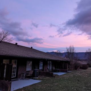 A serene sunset casts a colorful glow over the mountains and buildings.