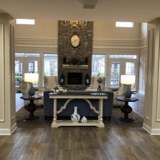 A modern living room with a central fireplace, elegant decor, and large windows allowing natural light to fill the space.