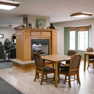 A cozy living room with a central fireplace, tables, and chairs.