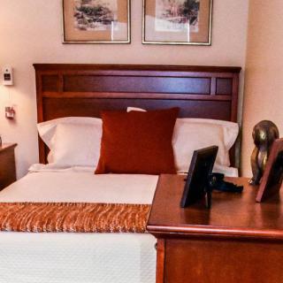 A cozy bedroom with a neatly made bed, featuring decorative pillows and bedside lamps.