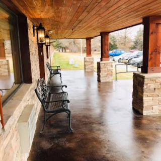 A serene porch area featuring benches and a wooden ceiling, perfect for relaxing and enjoying the outdoors.