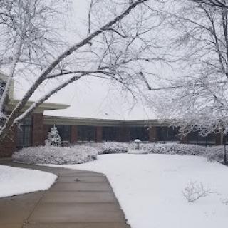 A serene winter scene with a snow-covered building and frosted trees.