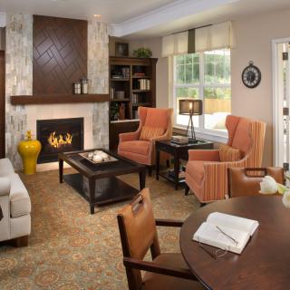 A cozy living room with a fireplace, armchairs, and bookshelves.