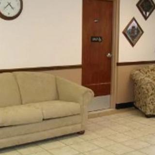 A waiting room with a couch, clock, and wall art.