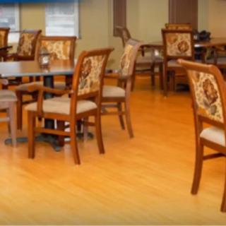 An indoor dining area with wooden chairs and tables on a wooden floor.