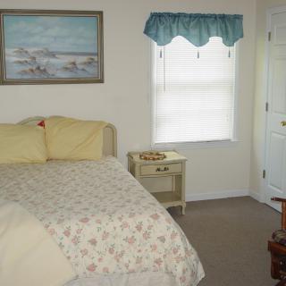 A cozy bedroom with a bed, nightstand, and window adorned with blue curtains.