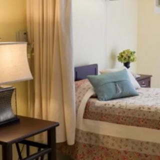 A cozy bedroom with a neatly made bed, adorned with pillows and a bedside lamp.