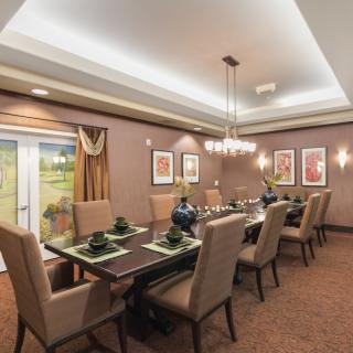 A beautifully decorated dining room with a long table, upholstered chairs, and elegant lighting.