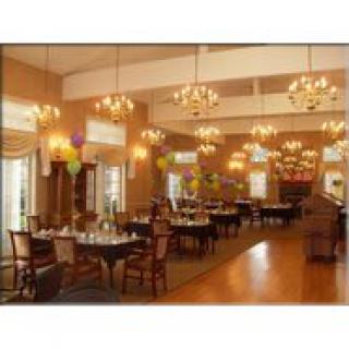 A spacious and elegantly decorated restaurant dining area with chandeliers, neatly arranged tables, and chairs.