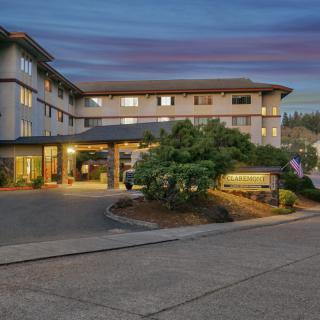 An evening view of a hotel entrance with landscaped surroundings.