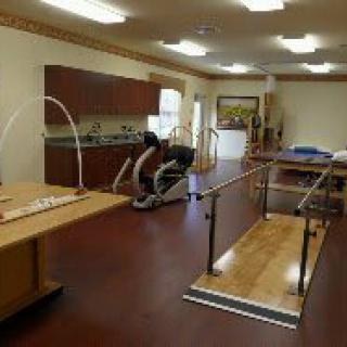 A rehabilitation therapy room equipped with exercise machines and parallel bars.