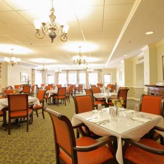 An elegant dining room with neatly arranged tables and chairs under chandeliers.