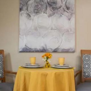 A cozy dining setup with a yellow tablecloth and elegant artwork in the background.