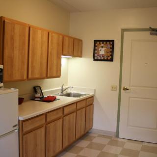 A compact kitchen area featuring wooden cabinets, a sink, and a refrigerator.