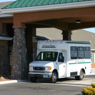 A white bus parked near the entrance of a building with a stone facade.