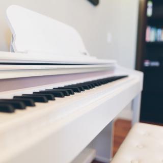 A sleek white piano in a cozy music room setting.