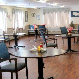 A spacious and inviting dining area with tables set for patrons, featuring bright lighting and a warm atmosphere.