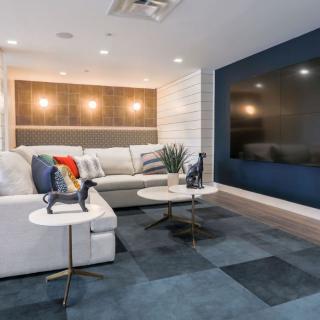 A modern living room featuring a large sofa, coffee tables, and a mounted television, with decorative lighting and a stylish rug.