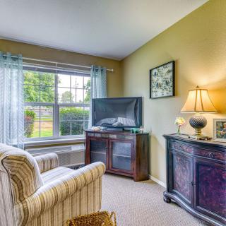 A cozy living room featuring a striped armchair, television, and decorative lamp.