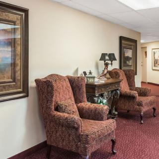 A cozy lobby area with upholstered armchairs and decorative paintings.
