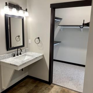 A bathroom with a wall-mounted sink and adjacent walk-in closet.