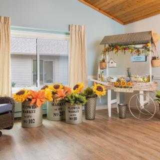 A bright and rustic interior decorated with sunflowers in metal buckets and a charming cart display.