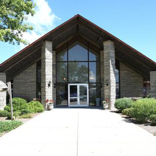 Front view of a church with stone walls and glass doors.
