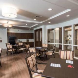 A modern dining area with neatly arranged tables and chairs, featuring wood flooring and stylish lighting.