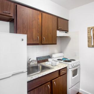 A compact kitchen with wooden cabinets, a refrigerator, stove, and sink.