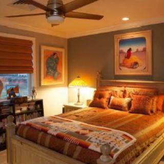 A cozy bedroom with warm lighting features decor and artwork on the walls.