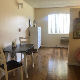 A cozy apartment interior with a small dining table, window, and hardwood floors.