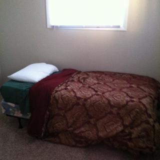 A simple bedroom with a single bed under a window.