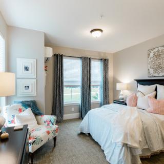 A beautifully designed bedroom featuring soft pastel accents and ample natural light.