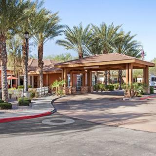 A resort entrance with palm trees and a roundabout driveway on a sunny day.