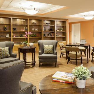A cozy living room with comfortable chairs, tables, and bookshelves.