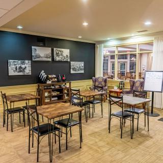 A cozy and modern cafe interior with wooden tables and chairs, featuring artwork on the walls.