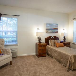 A cozy bedroom with a single bed, nightstands, and an armchair by the window.