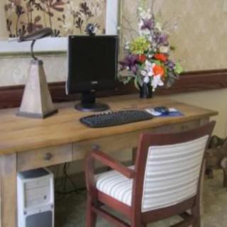 A cozy office setup with a wooden desk, computer monitor, keyboard, and a floral arrangement.