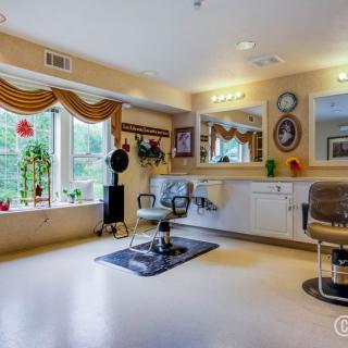 A well-lit hair salon interior featuring a styling chair, large mirror, and decorative elements by the window.