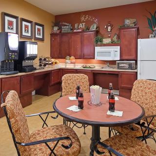 A cozy kitchen and dining area featuring a round table with chairs, a coffee station, and modern appliances.