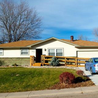 A suburban house with a well-maintained yard and a car parked in the driveway.