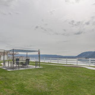 A serene outdoor gathering area overlooking the water, featuring a tent and patio furniture against a cloudy sky.