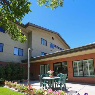 A sunny day at a residential building with a garden patio and outdoor seating.
