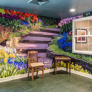 A vibrant mural of a garden scene with colorful flowers and stairs enhances the room's interior design.