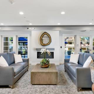 A modern living room with two gray sofas, a central coffee table, and a fireplace adorned with a decorative mirror.