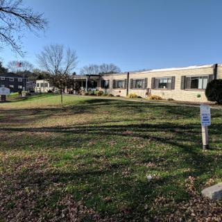 A view of a building surrounded by grass and trees under a clear blue sky.