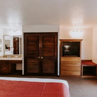 A cozy hotel room with wooden furniture, a television, and a mirror.