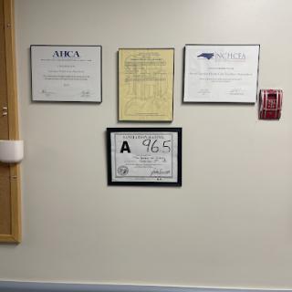 A collection of professional certificates and awards displayed on a wall.